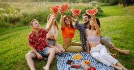 Sommer: Eine Gruppe Freunde essen Wassermelone in guter Laune beim Picknick